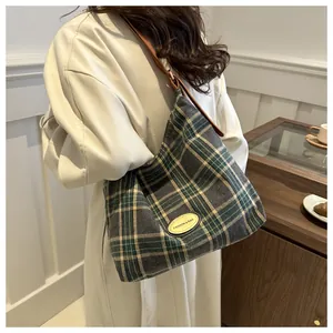 Détail d'un sac cabas en toile à carreaux verts avec une bandoulière en cuir