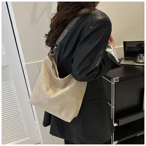 Detail of beige hobo bag with ethnic embroidery strap on model in black leather jacket
