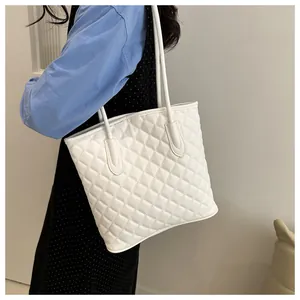 Detailed view of white quilted tote bag with diamond pattern and long shoulder strap