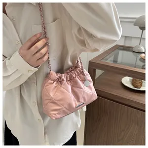 Sac seau matelassé rose avec chaîne argentée porté par un mannequin dans un décor intérieur