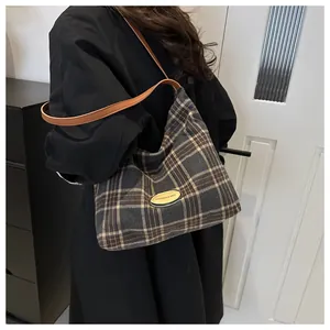 Détail du sac cabas en toile à carreaux avec anses en cuir marron et patch logo mode
