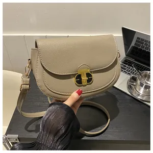 Detail of beige saddle bag showing textured leather and stylish gold T-shaped clasp