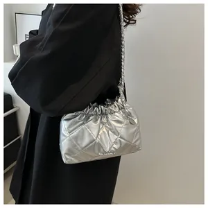 Détail du sac seau matelassé argenté avec fermeture à cordon et bandoulière chaîne