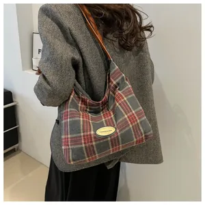 Détail du sac cabas à carreaux rouge et gris avec texture tweed et plaque logo mode