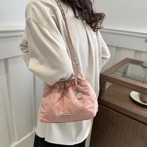 Sac seau rose matelassé avec bandoulière chaîne et cordon, porté par un mannequin