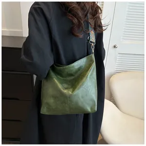 Detail of dark green leather shoulder bag with vintage ethnic woven wide strap