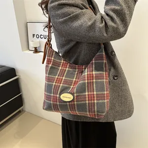 Sac bandoulière rétro à carreaux avec sangle en cuir porté par un mannequin en blazer