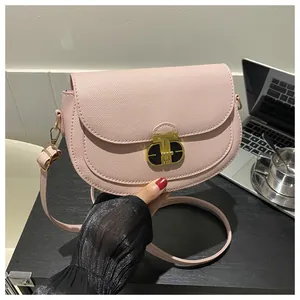 Detailed close-up of pink textured saddle bag with gold metal clasp and crossgrain finish