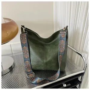 Detail of dark green vintage tote bag featuring a colorful jacquard ethnic shoulder strap