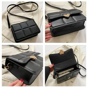Dettaglio di una borsa a tracolla trapuntata nera con fibbia a cuore dorata e cinturino