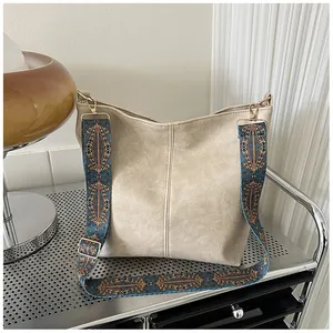 Detail of beige faux leather tote bag with ethnic woven strap and pebble texture