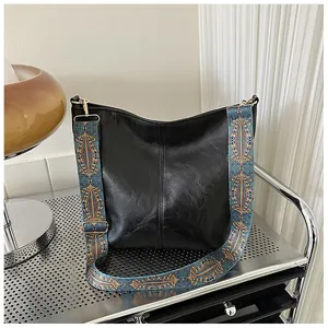 Close-up of black soft leather tote bag featuring a vintage geometric wide shoulder strap