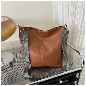 Detail of brown faux leather bucket bag with colorful ethnic geometric jacquard shoulder strap