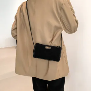 Sac bandoulière cylindre noir minimaliste avec logo doré sur texture en daim