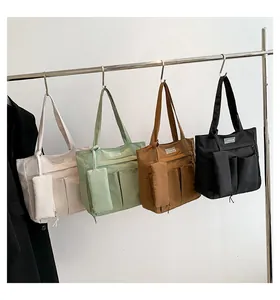 Vista detallada de bolsos tote grandes de nailon en beige, verde, marrón y negro con bolsillos