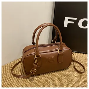 Detailed macro view of caramel PU leather texture and FASHION lettering on Boston handbag