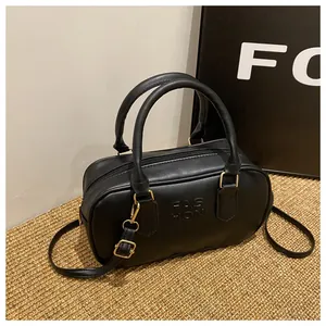 Close-up of black PU leather handbag with FASHION embossed logo and gold metal hardware