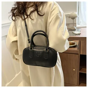 Detail view of black cylinder handbag featuring FASHION embossing and gold metal hardware