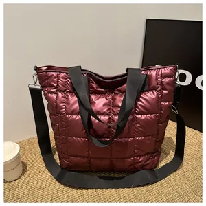 Detail of burgundy quilted tote bag with square stitching and adjustable black strap