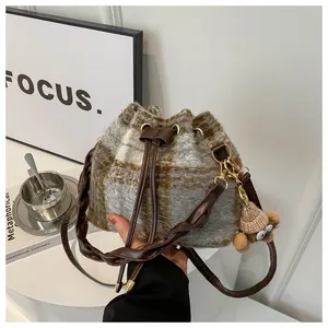Detail of plaid bucket bag featuring a cute bear plush pendant and leather drawstring