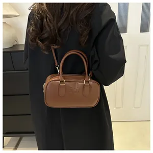 Detail of vintage brown leather handbag with embossed fashion logo and adjustable strap
