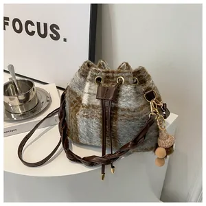 Detail of vintage plaid bucket bag with drawstring closure and pinecone charm accessory