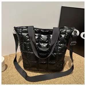 Detail of black quilted tote bag showing shiny nylon texture and wide strap
