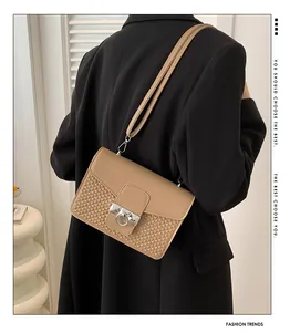 Detail of beige shoulder bag featuring woven texture and silver metal ring buckle