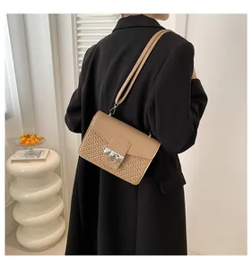 Detail view of khaki shoulder bag featuring textured paneling and silver metal ring buckle