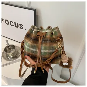 Close-up of retro plaid bucket bag with woven leather strap and monster charm