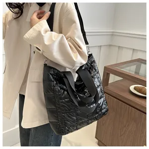 Close-up of black quilted puffer tote bag with glossy finish and thick padded texture