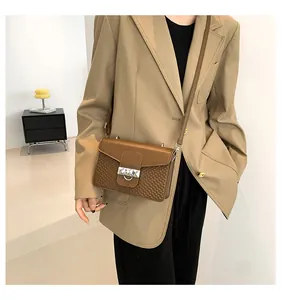 Close-up of brown crossbody bag with quilted texture and silver metal buckle detail