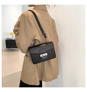 Detail of black crossbody bag with woven texture and silver ring buckle worn by a model