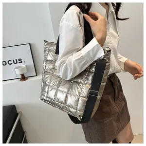 Detail of silver quilted tote bag with wide black strap on a model for daily commute