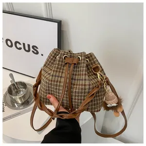 Close-up of retro plaid drawstring bucket bag with decorative monster plush keychain