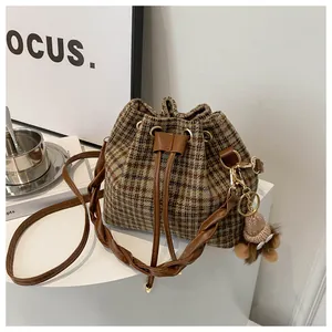 Detail of vintage plaid drawstring bucket bag with a plush bear charm and dual straps