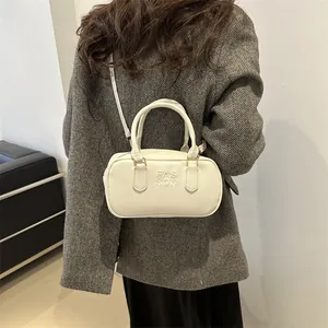 Minimalist beige leather cylinder handbag with embossed FAS HON text worn by model
