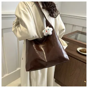 Detalle de bolso tote de cuero marrón oscuro con colgante de estrella suave