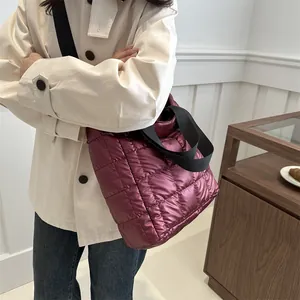 Burgundy quilted puffer tote bag with black strap in a minimalist lifestyle setting