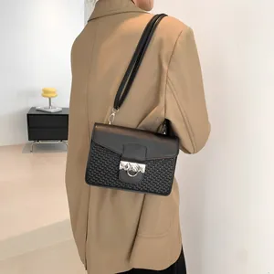 Chic black flap crossbody bag with woven texture and silver square lock worn by a model