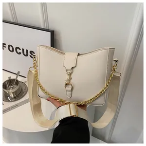 Détail du sac bandoulière en cuir crème avec chaîne dorée et sangle tissée élégante