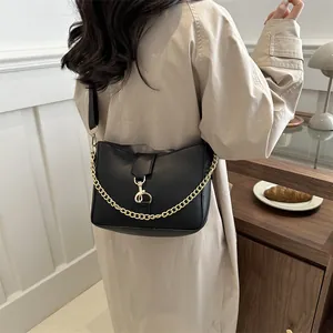 Sac à bandoulière noir demi-lune avec chaîne dorée porté par un mannequin en intérieur