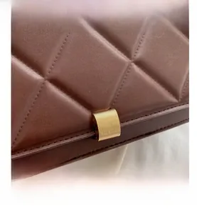 Macro detail of brown quilted leather texture and brushed gold metal fastener