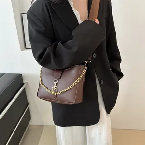 Sac bandoulière marron rétro avec chaîne dorée et large sangle sur modèle