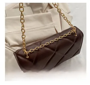 Close-up of polished gold chain strap and brown quilted leather texture on crossbody bag