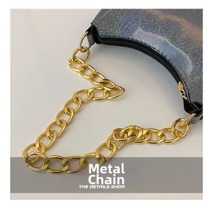 Detail of the chunky gold hardware chain on the silver holographic sequin shoulder bag