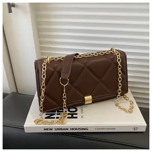 Close-up of dark brown quilted crossbody bag with gold chain and metal buckle detail