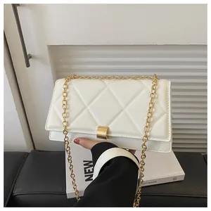 Detailed close-up of white quilted leather texture and golden metal chain of the handbag