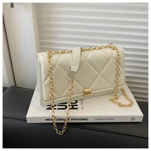 Detail of cream quilted crossbody bag with gold chain strap and square metal clasp