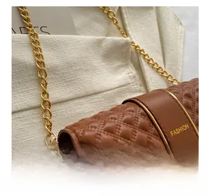 Close-up of brown quilted bag with gold chain strap, metal lock, and fashion text detail